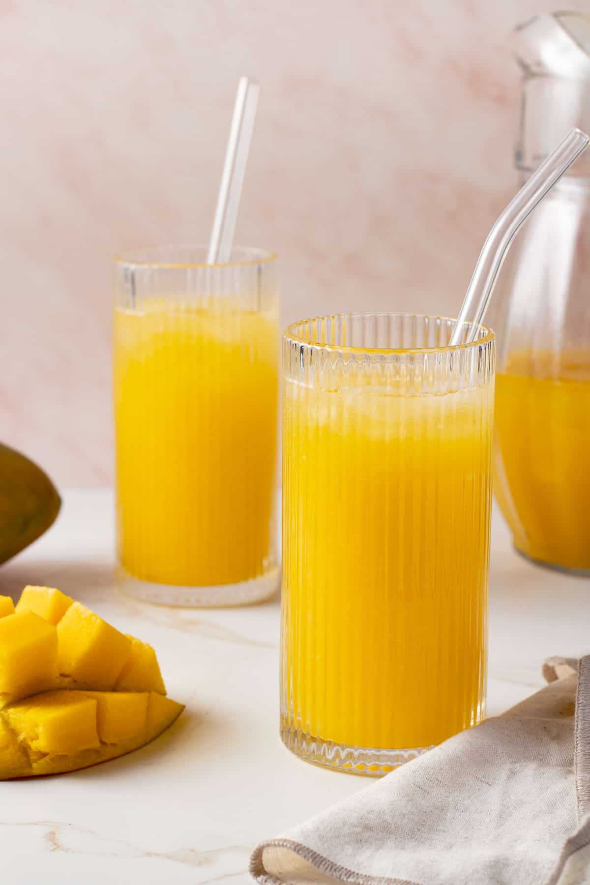Close up image of mango lemonade in a glass with fresh mangos nearby.