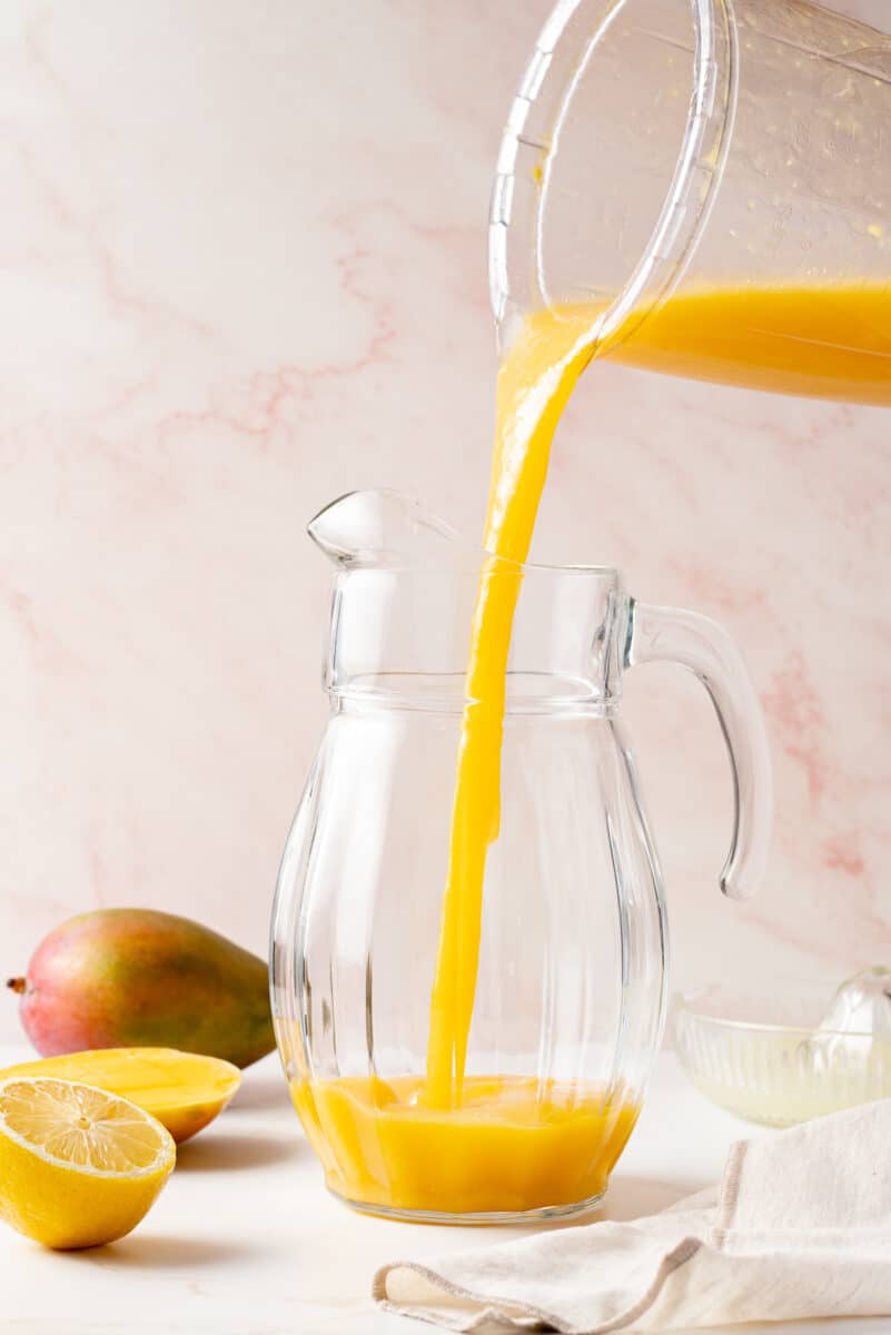 Mango puree being poured in a pitcher.