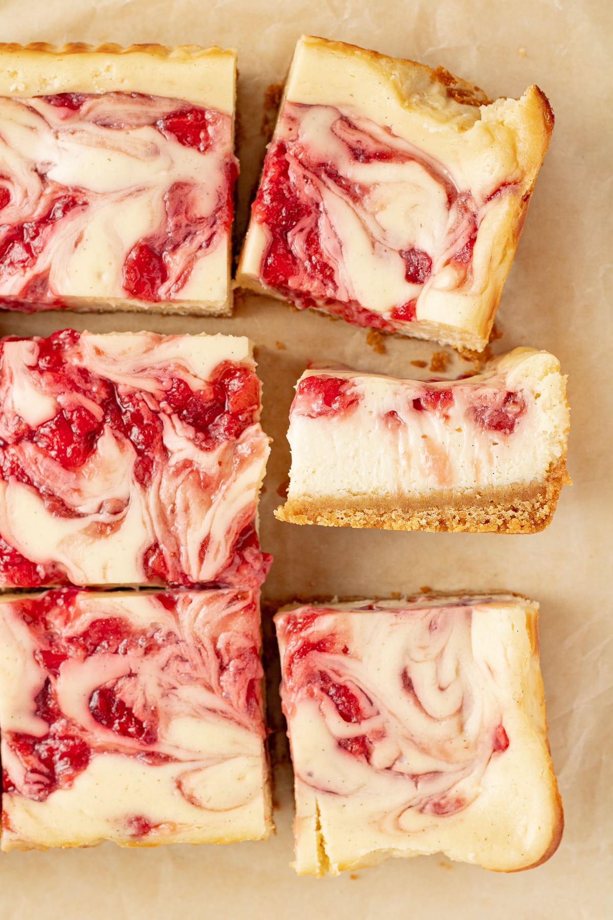 Cut strawberry cheesecake bars on parchment paper.